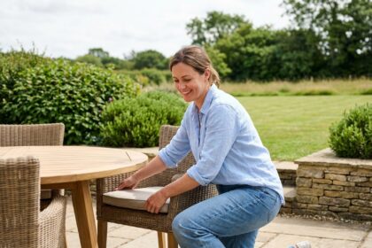 Femme souriante arrangeant mobilier extérieur dans un jardin